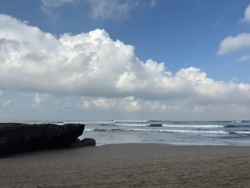 A flat black rock and breaking waves at Batu Bolong beach